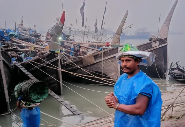 A labourer of fisheries ghat standing in front of a boat