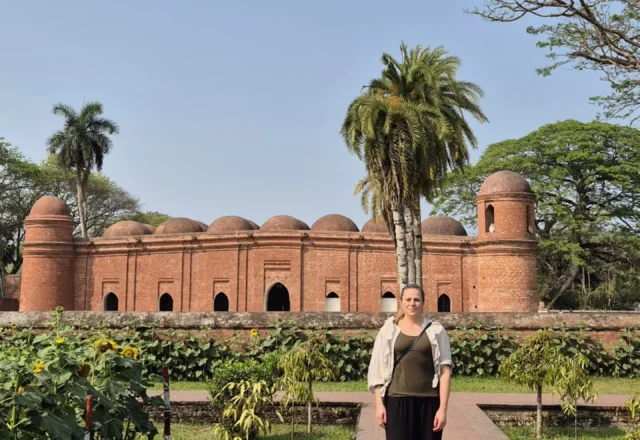 A tourist in front of the historical Sixty Dome Mosque