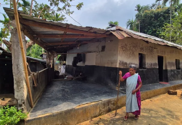 An older woman standing in front of an old house