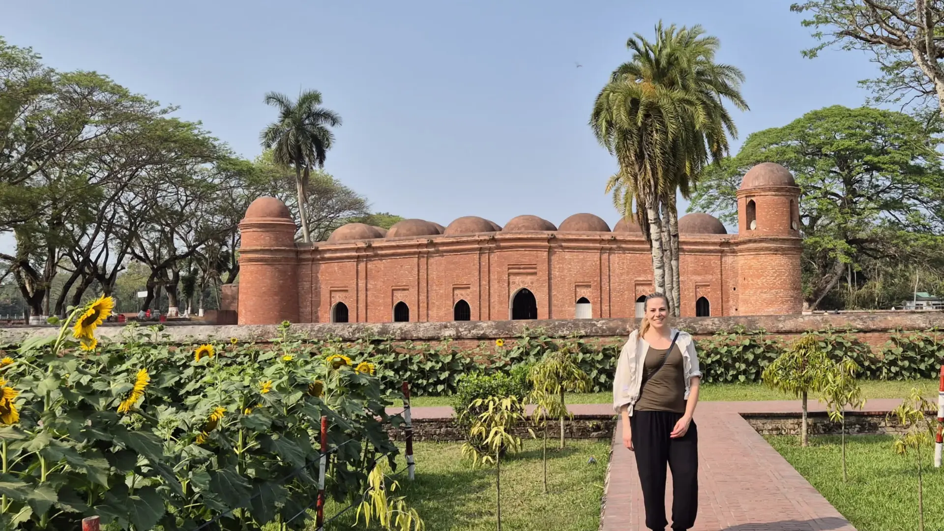 Side view of Sixty Dome Mosque with a tourist