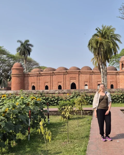Side view of Sixty Dome Mosque with a tourist