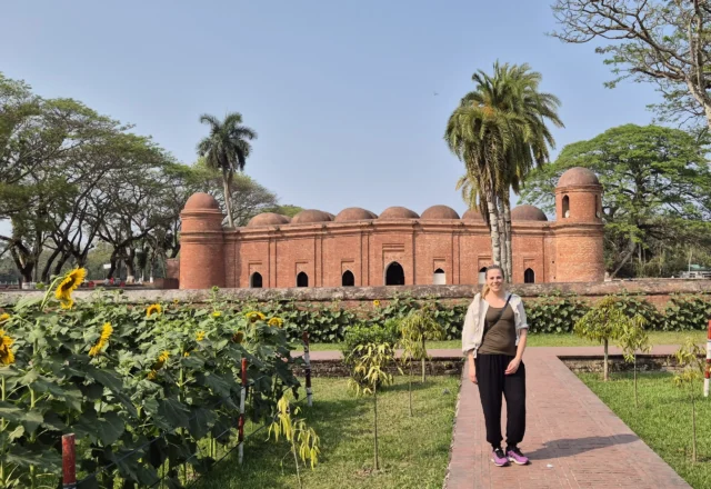 Side view of Sixty Dome Mosque with a tourist