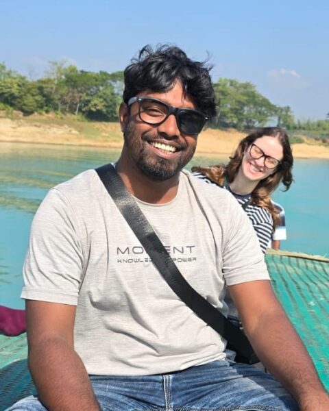Abu Raihan Morshed, Evergreen Bangladesh Tours guide, smiling on a boat on a lake in Bangladesh with a happy guest behind him