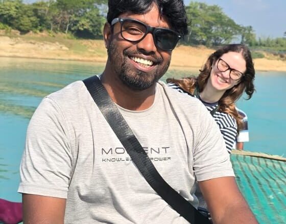 Abu Raihan Morshed, Evergreen Bangladesh Tours guide, smiling on a boat on a lake in Bangladesh with a happy guest behind him