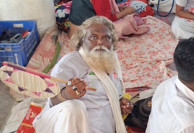 Baul elder with a hand fan resting at the Lalon Mela
