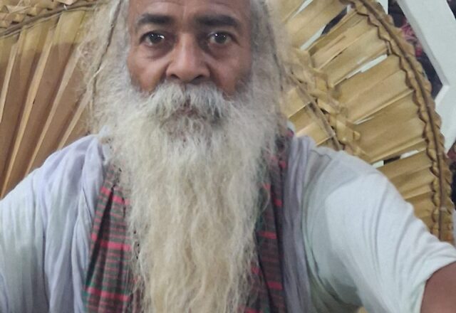 Baul sadhu with a long white beard and a checked scarf at the Lalon Mela